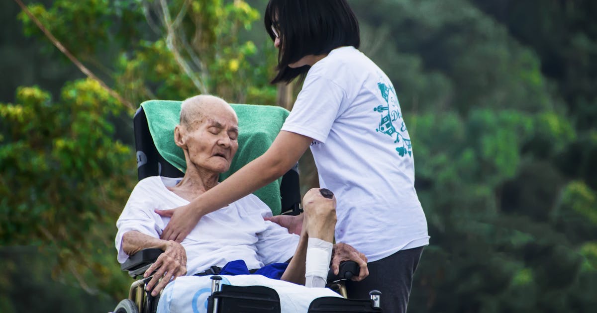 Home health caregiver assisting elderly patient